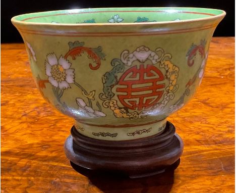 A Chinese circular bowl, decorated in polychrome enamels with flowers and symbol on an apple green ground, 12.5cm diam, red f