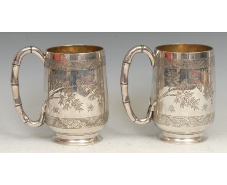 A pair of Chinese silver pint mugs, each engraved with with birds on branches, and insects, within borders of dragons, faux b