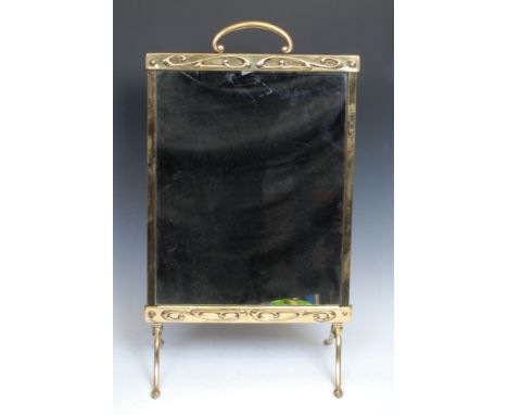 An Art Nouveau brass fire screen, arched handle, mirrored banner, the frieze and apron embossed with whiplash scrolls, 65cm h
