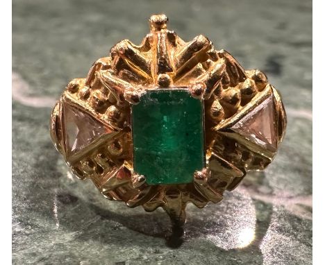 An emerald and diamond ring, rectangular emerald cut emerald approx 0.60ct, within ornate shield crest with two triangular cu