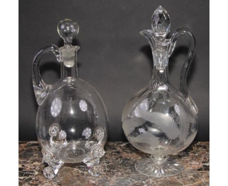 A 19th century ovoid glass decanter and stopper, the scroll feet applied with lion masks, 30cm high; another, etched with fer