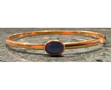 A Opal set indistinctly marked gold bangle, rounded body set with a single deep blue green oval opal, approx 7.5mm x 6mm, rol