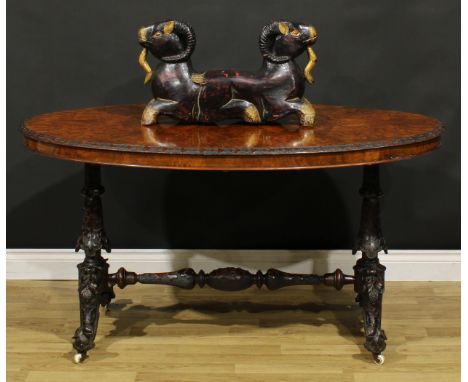 A Victorian Irish walnut and mahogany centre table, oval quarter-veneered top with carved edge, the underframe profusely carv