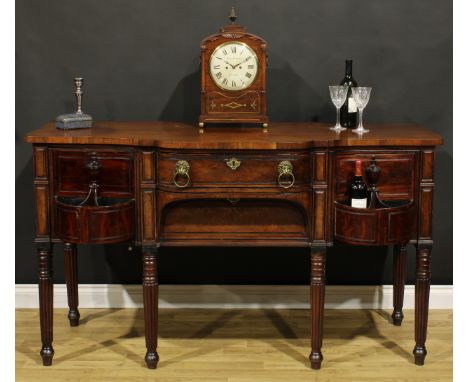 An unusual Regency mahogany sideboard or serving table, slightly oversailing top above a central frieze drawer and an apron d