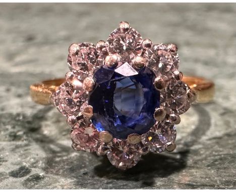 An 18ct gold, sapphire and diamond ring, the central round facet cut stone within eight round brilliant cut diamonds, total a