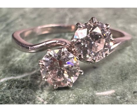 A two-stone diamond cross-over ring, the two round brilliant cut stones claw set, each approximately 0.52ct, total estimated 