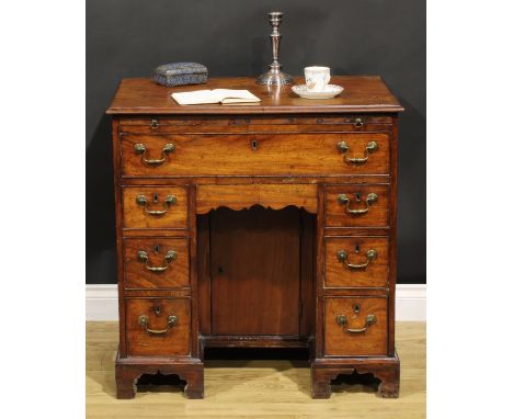 A George III mahogany kneehole desk, the ovolu moulded top above a brushing slide, axe head handles, above one long and six s