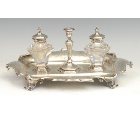 A Victorian silver shaped rectangular standish, central taper stick flanked by a pair of inkwells, bright-cut engraved with s