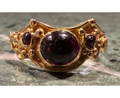 An 18ct gold garnet ring, set with three oval and circular cabochon red garnets, shaped scrolling crest, 18ct gold shank, siz