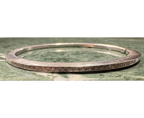 A diamond set white metal hinge bangle, razor edge set with twenty five round brilliant cut diamonds, total estimated diamond