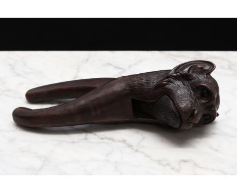 Nutcrackers - a Black Forest novelty lever-action nut cracker, carved as the head of a monkey, 19cm long, early 20th century 