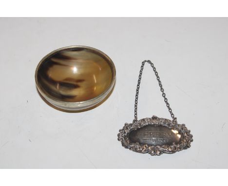 A horn bowl with white metal rim and a silver decanter label 
