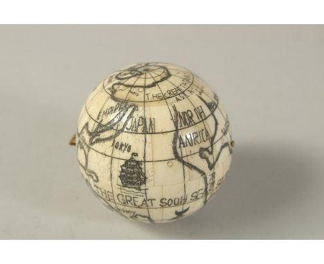 AN ETCHED BONE GLOBE OF THE WORLD COMPASS. 6cms diameter.