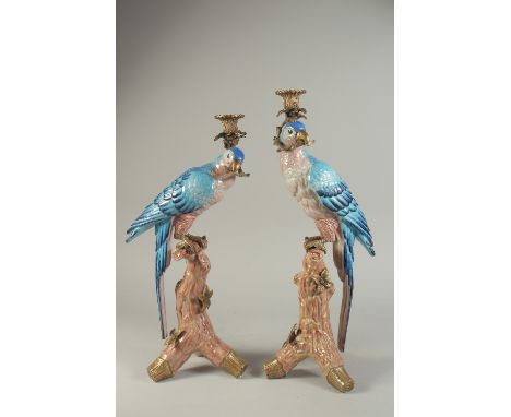 A PAIR OF LIGHT BLUE PARROT CANDLESTICKS on rustic bases. 20ins high.