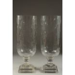 A PAIR OF GLASS STORM LANTERNS on square stepped bases. 16ins high.