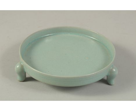 A CHINESE CELADON GLAZED RU WARE TRIPOD CIRCULAR STAND. 15cms diameter.