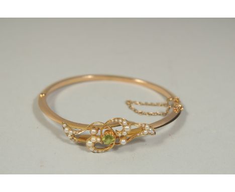 AN EDWARDIAN GOLD BANGLE set with seed pearls.
