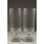 A PAIR OF GLASS STORM LANTERNS on square stepped bases. 16ins high.