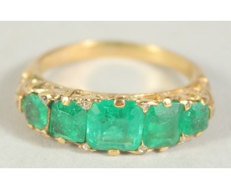 A SIX STONE EMERALD GOLD RING. Size M.