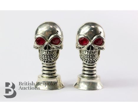 A pair of silver plated unusual skull condiments with glass eyes, ideal for Halloween, approx 5 cms h.&nbsp;