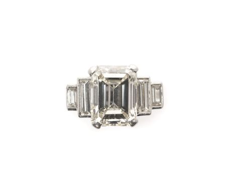DIAMOND RING, 1950s claw set with a rectangular step-cut diamond measuring approximately 11.6 x 8.7 x 5.7, set between gradua
