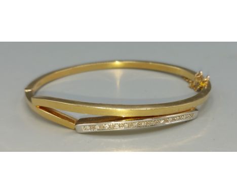 An 18ct gold bangle inset with thirteen diamonds, 6cms by 5cms, 13.4gms 