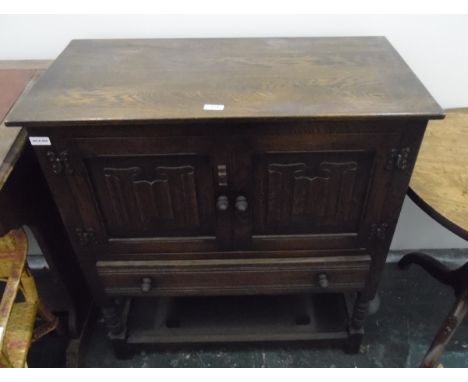 Reproduction dwarf oak cabinet enclosed by two linenfold panel doors over one long drawer and with an under-tier 