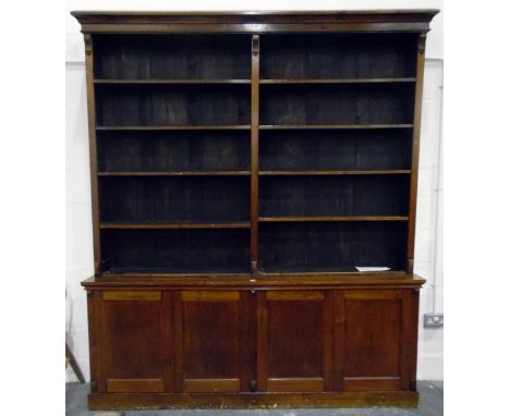 Stained wood library bookcase having five-tier open upper section and on a cupboard base, enclosed by four panel doors and on