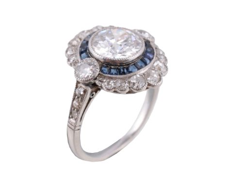  An Art Deco diamond and sapphire dress ring  , circa 1925, the oval shaped panel with a central old brilliant cut diamond es