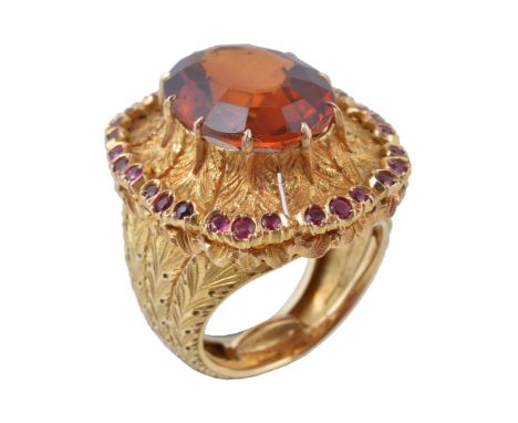  A 1970s citrine and ruby ring by Buccellati,   the central oval cut citrine, claw set within a textured feathered surround t