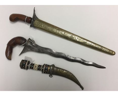A collection of three daggers: one Middle Eastern Jambiya with 135mm long curved signle edged blade with three fullers and so