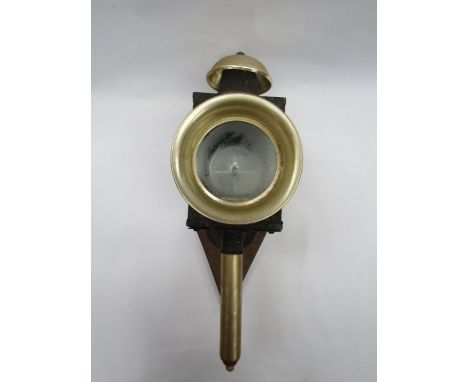 A metal coaching lamp mounted on diamnd shaped wooden back 