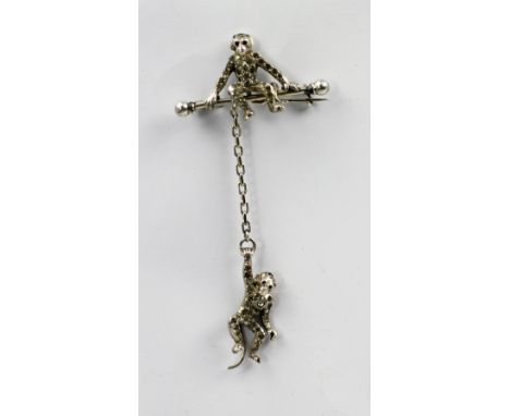 A paste set acrobatic monkeys brooch, the first monkey sitting on a flying trapeze bar with curled tail, the other suspended 