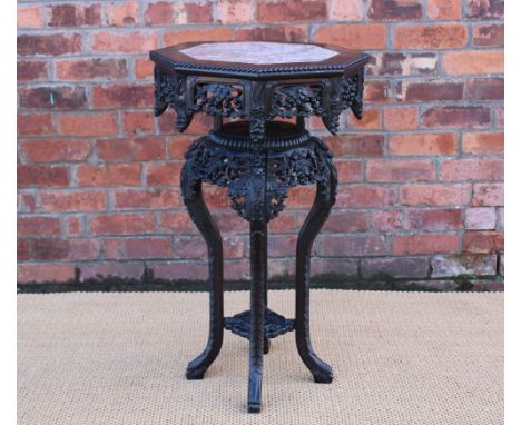 A late 19th century Chinese carved hardwood jardiniere stand, with marble inset octagonal top, with a circular underside, on 
