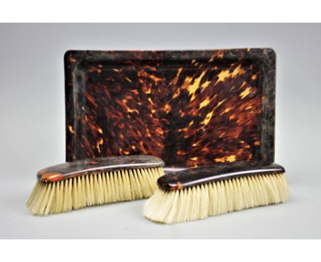 An Edwardian tortoiseshell tray, 28cm x 18cm, with two tortoiseshell backed brushes (3)   CONDITION REPORT:  General light ag