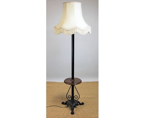 A walnut and iron standard lamp, with circular shelf, on triform scroll base, 140cm H CONDITION REPORT: Lighting lots are sol