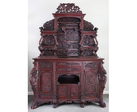 A highly decorative Chinese carved softwood dresser, with phoenix surmount above an arrangement of seven shelves, above two d