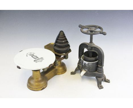 A late 19th century cast iron cheese scale, with ceramic plateau, 38cm wide, with a small French cast iron fruit press, on pa