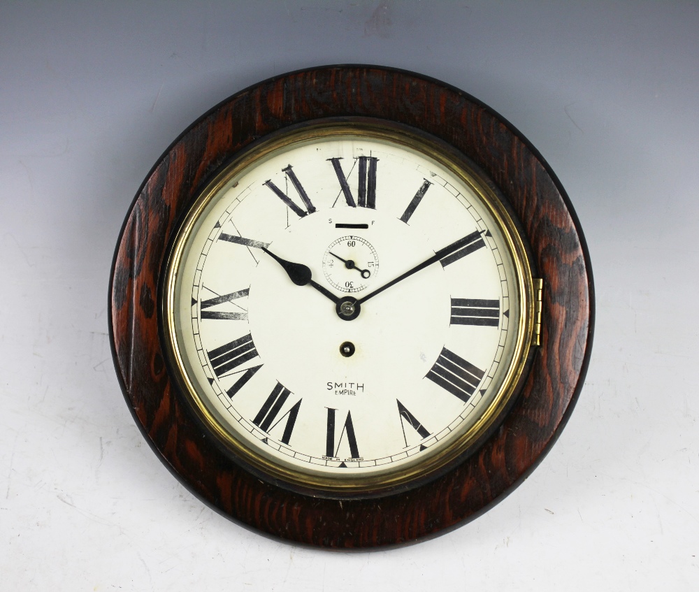 A 1930's Smiths Empire wall clock, the stained pine case enclosing a ...