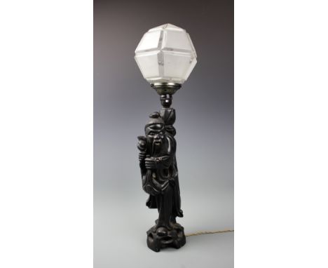 A Japanese carved hardwood lamp, modelled as a travelling sage on pierced base, with an Art Deco style frosted glass shade, 6