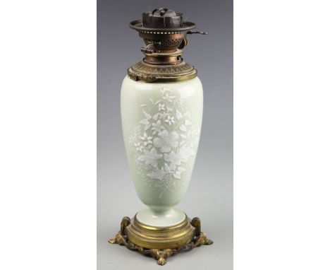 A late 19th century pate sur pate oil lamp, possibly French, decorate with flowers against a celadon ground, lacking handles 