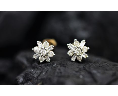 A pair of diamond set stud earrings, each of snowflake form and set with brilliant and baguette cut diamonds, all set in whit