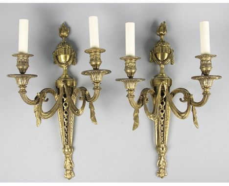 A pair of George III style gilt brass twin branch wall lights, the torch shaped sconce arms hung with swags, the pierced back