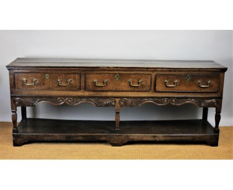 A George III oak dresser, with three plank top above three drawers with later carved serpentine apron, on square legs and pot