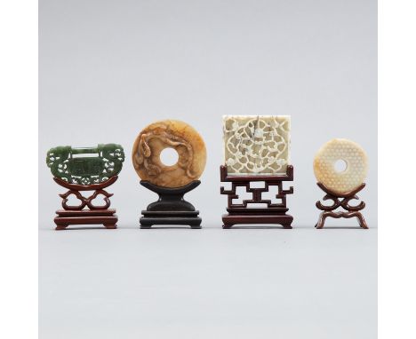 Group of four Chinese jade carvings. One round plaque with shou symbols in the middle, one depicting a bi surrounded by wrest