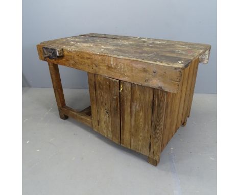 A vintage stained pine workbench, with Whitmore vice and cupboards under. 123x73x70cm.