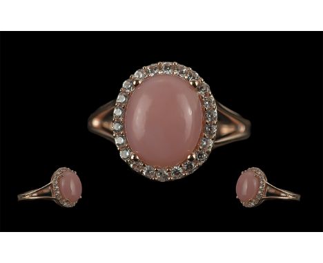 Pink Opal and White Zircon Ring, an oval cabochon cut pink opal of 3cts, the rare colour mined in Peru, surrounded by a fine 