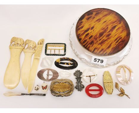 A 1920s powder bowl containing a quantity of vintage buckles and carved bone items.
