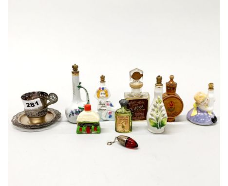 A group of antique and vintage perfume bottles with a white metal cup and saucer.