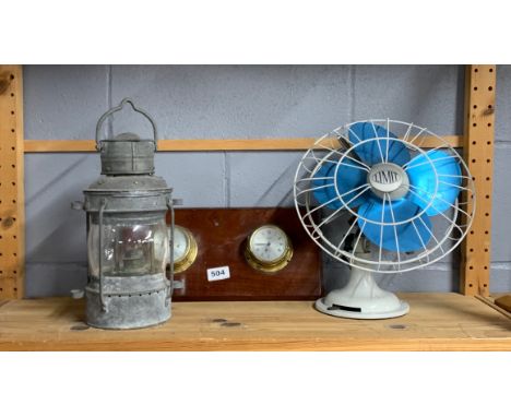 A wall mounted clock barometer with a ships oil lamp and a vintage Limit desk fan.